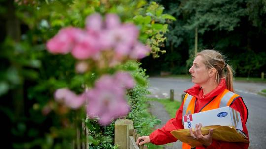 Postwoman walking delivering mail